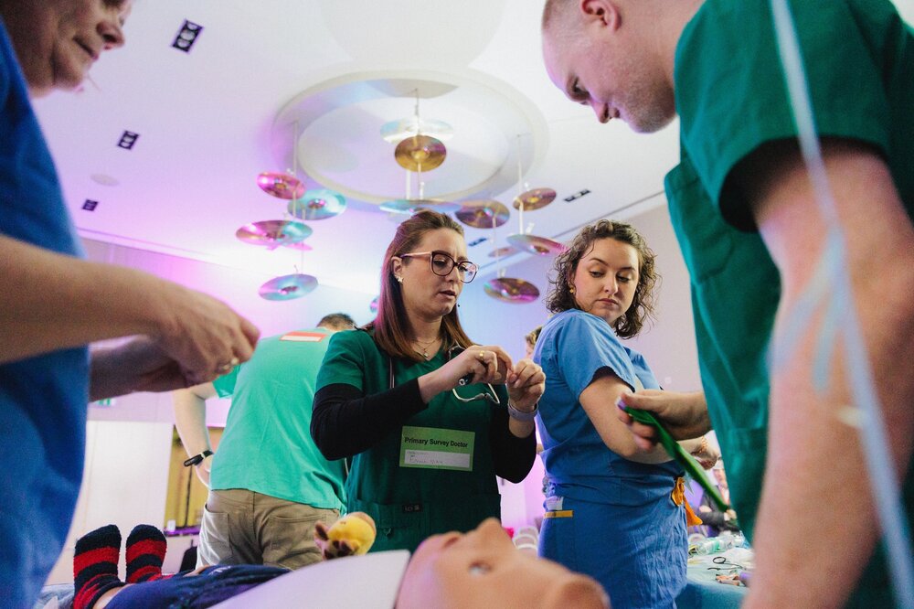 A group of people in scrubs putting on a dummyAI-generated content may be incorrect.